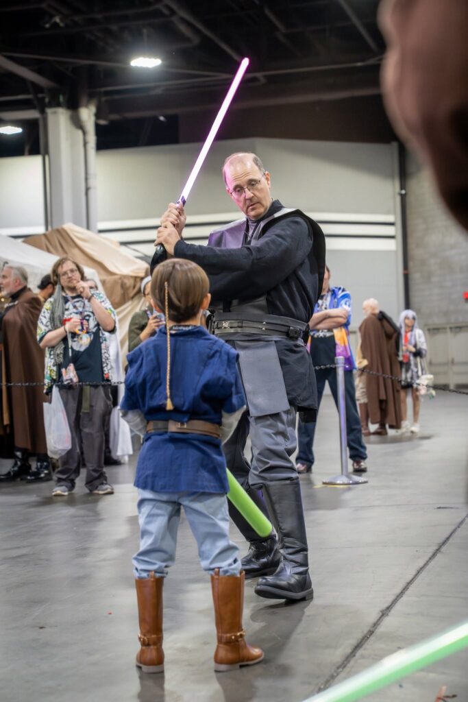 a Dark Jedi brandishing a lightsaber before a Padawan